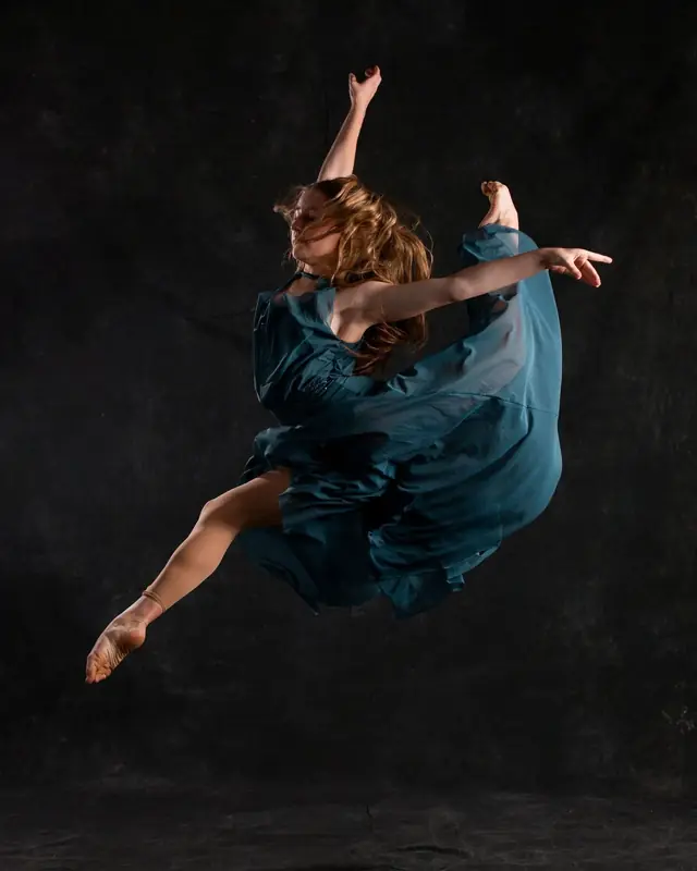 Faith Staples, dance instructor, captured mid-leap against a dark backdrop