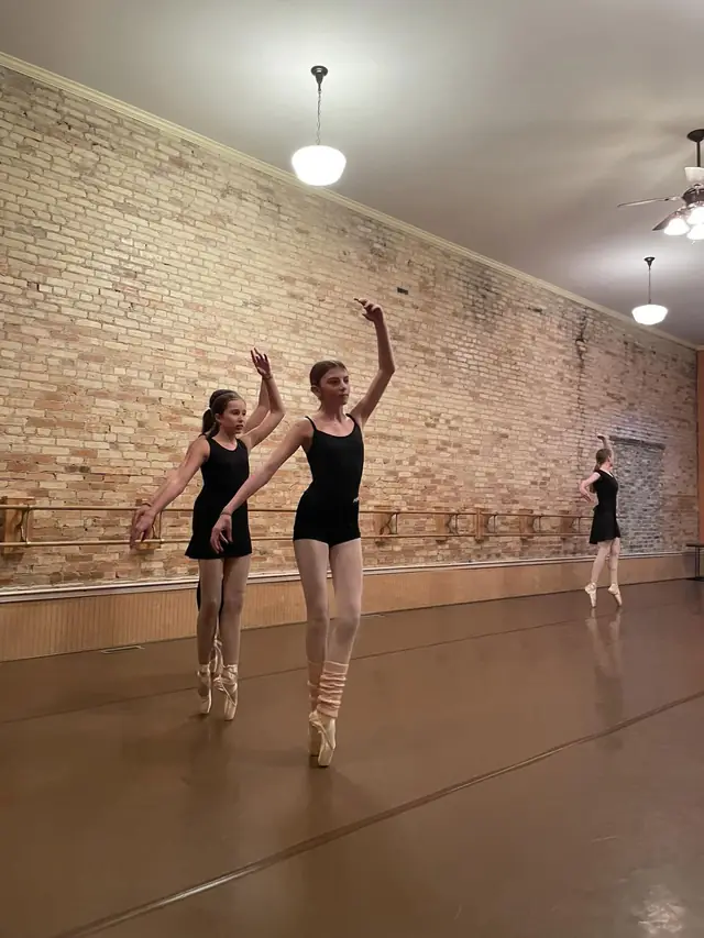 Two dancers en pointe at the barre in the Haslett studio